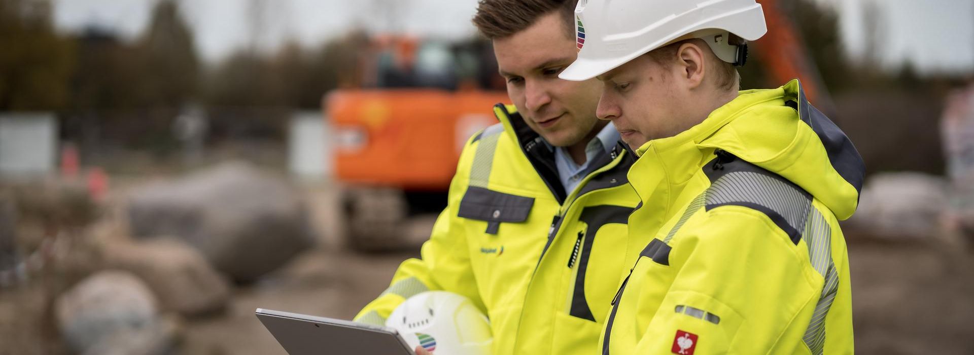 Zwei Mitarbeiter des Rechenzentrum Teams stehen an einer Baugrube und prüfen Daten auf einem Tablet.